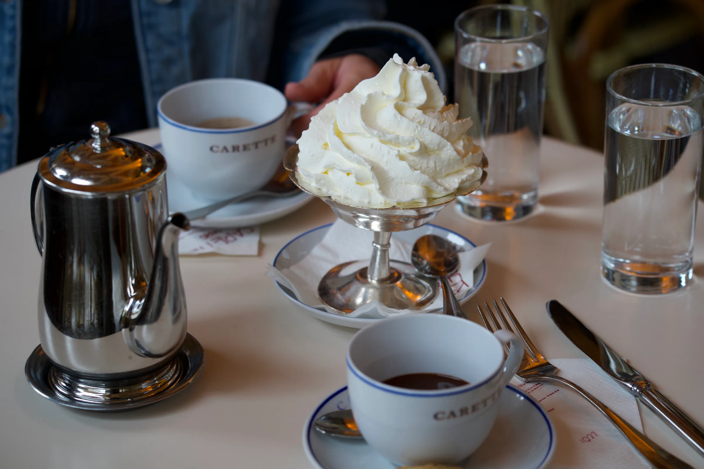 Chantilly cream, hot chocolate and a silver pot on a Paris cafe table