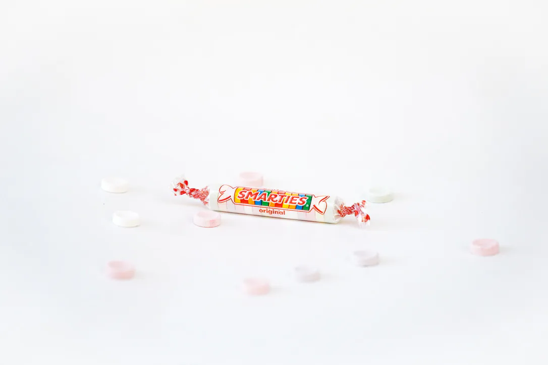A wrapped roll of pastel candy arranged on white
